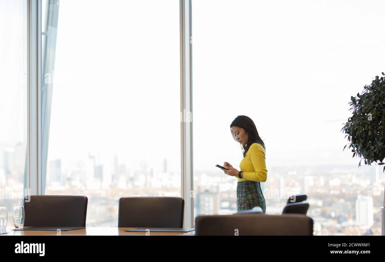 Geschäftsfrau mit Smartphone im Hochhaus-Konferenzraum Stockfoto