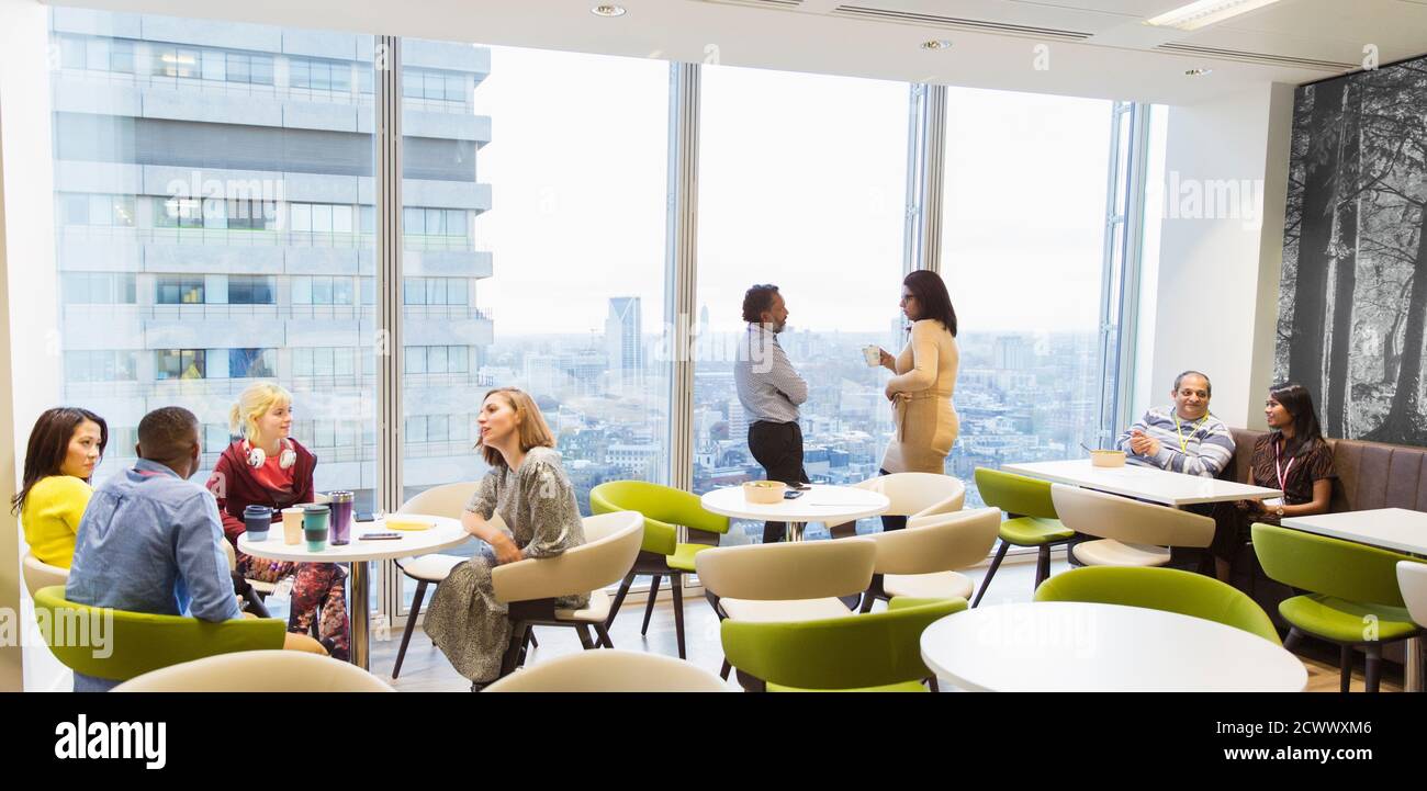 Geschäftsleute unterhalten sich und trinken Kaffee in der Cafeteria im Hochhaus Stockfoto