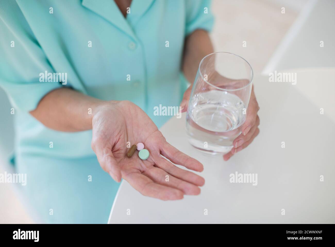 Ältere Frau, die Vitamine mit Wasser nimmt Stockfoto