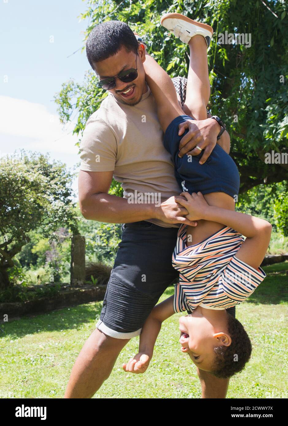 Verspielter Vater hält Sohn auf den Kopf in sonnigen Sommer Hinterhof Stockfoto