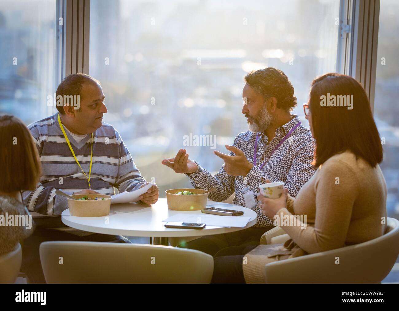 Geschäftsleute unterhalten sich und essen Mittagessen in der Bürokantine Stockfoto