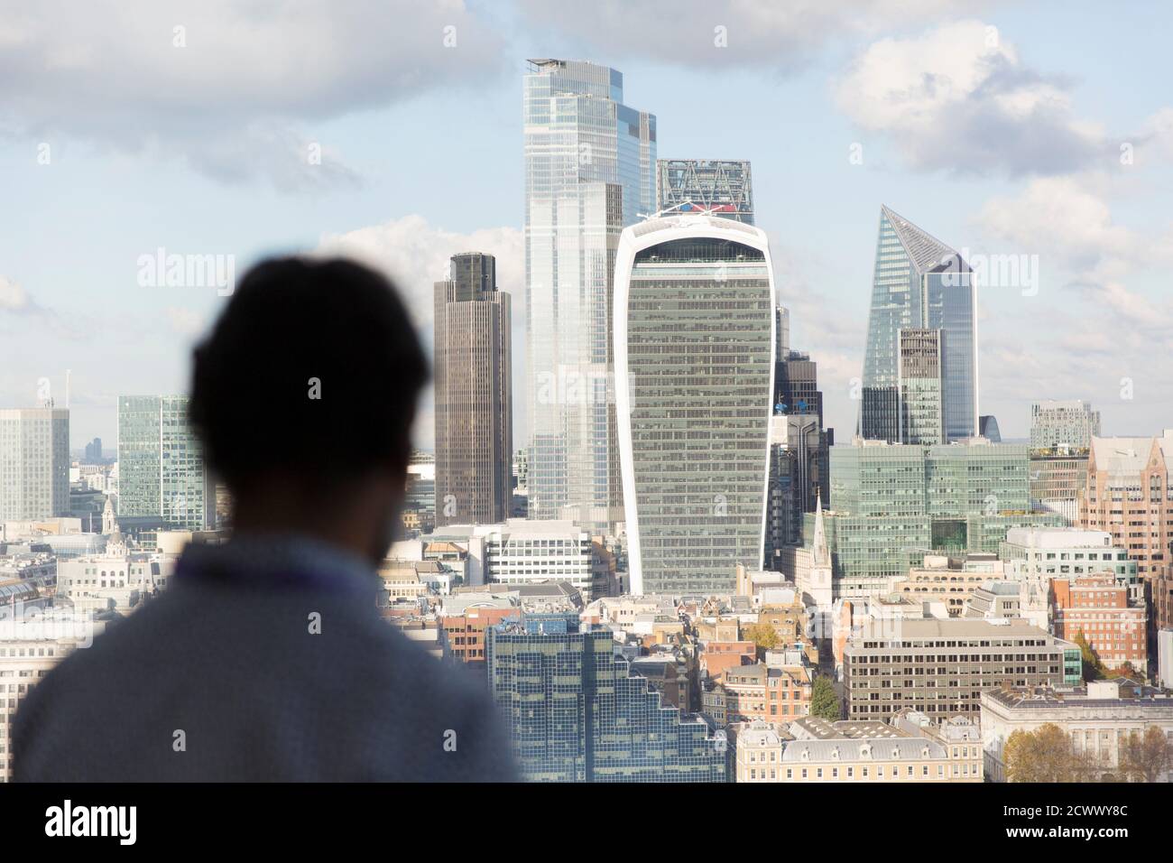 Geschäftsmann, der vom Bürofenster aus das sonnige Stadtbild Londons betrachtet Stockfoto