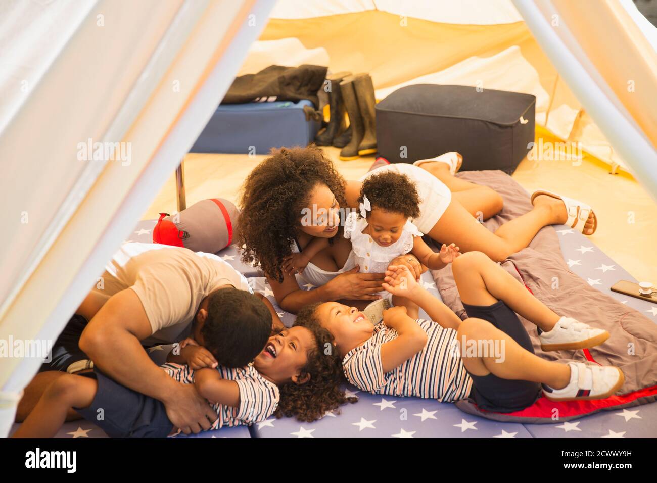 Verspielte Familie kitzelt und lacht im Zelt Stockfoto