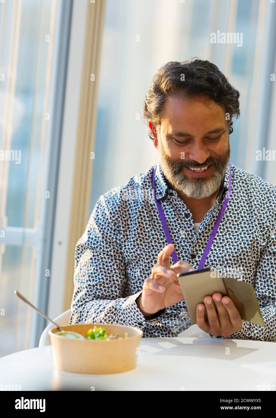 Lächelnder Geschäftsmann mit Smartphone beim Mittagessen Stockfoto