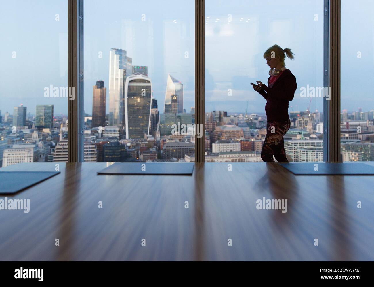 Geschäftsfrau mit Smartphone im Hochhaus-Bürofenster, London, Großbritannien Stockfoto