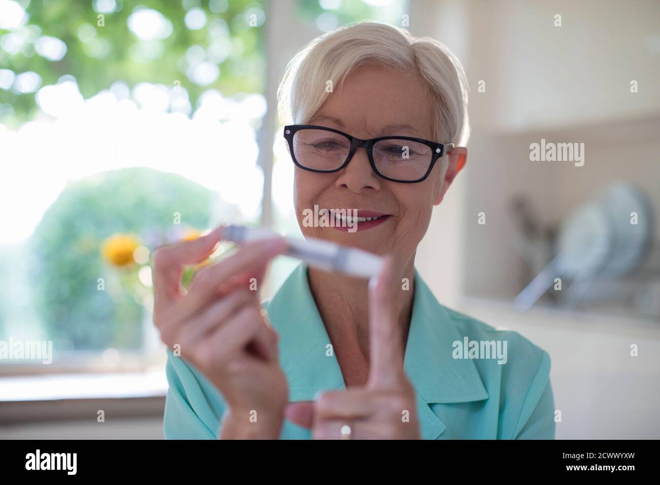 Ältere Frau mit Diabetes mit Blutzuckermessgerät am Finger Stockfoto