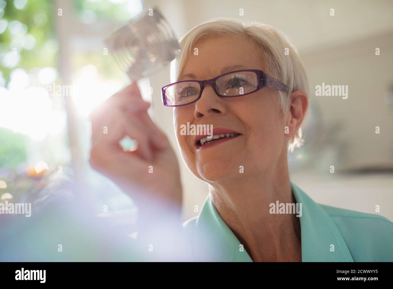 Neugierige ältere Frau untersucht Würfel im Sonnenlicht Stockfoto