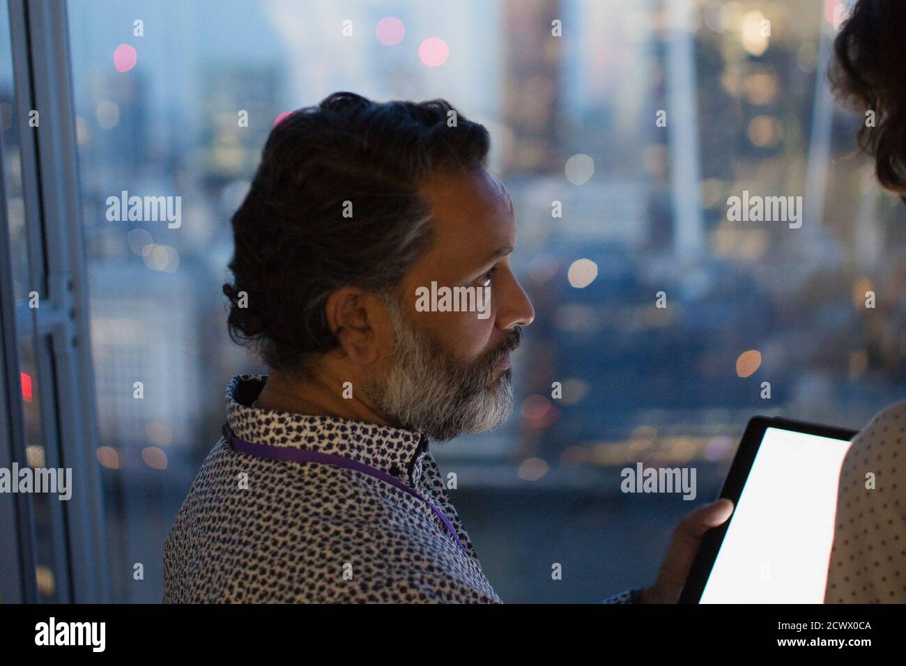 Geschäftsmann mit digitalem Tablet, der spät im Büro arbeitet, London, Großbritannien Stockfoto