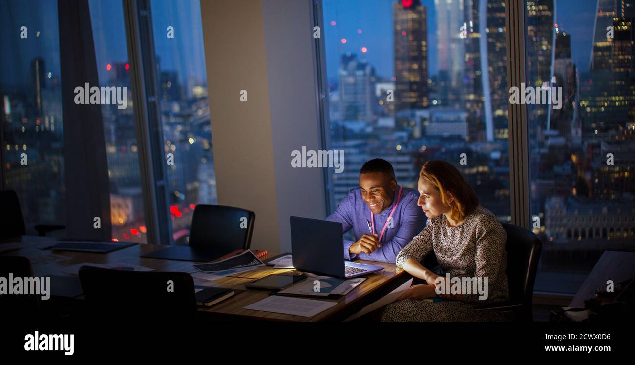 Geschäftsleute, die spät am Laptop im Hochhaus in London arbeiten Stockfoto