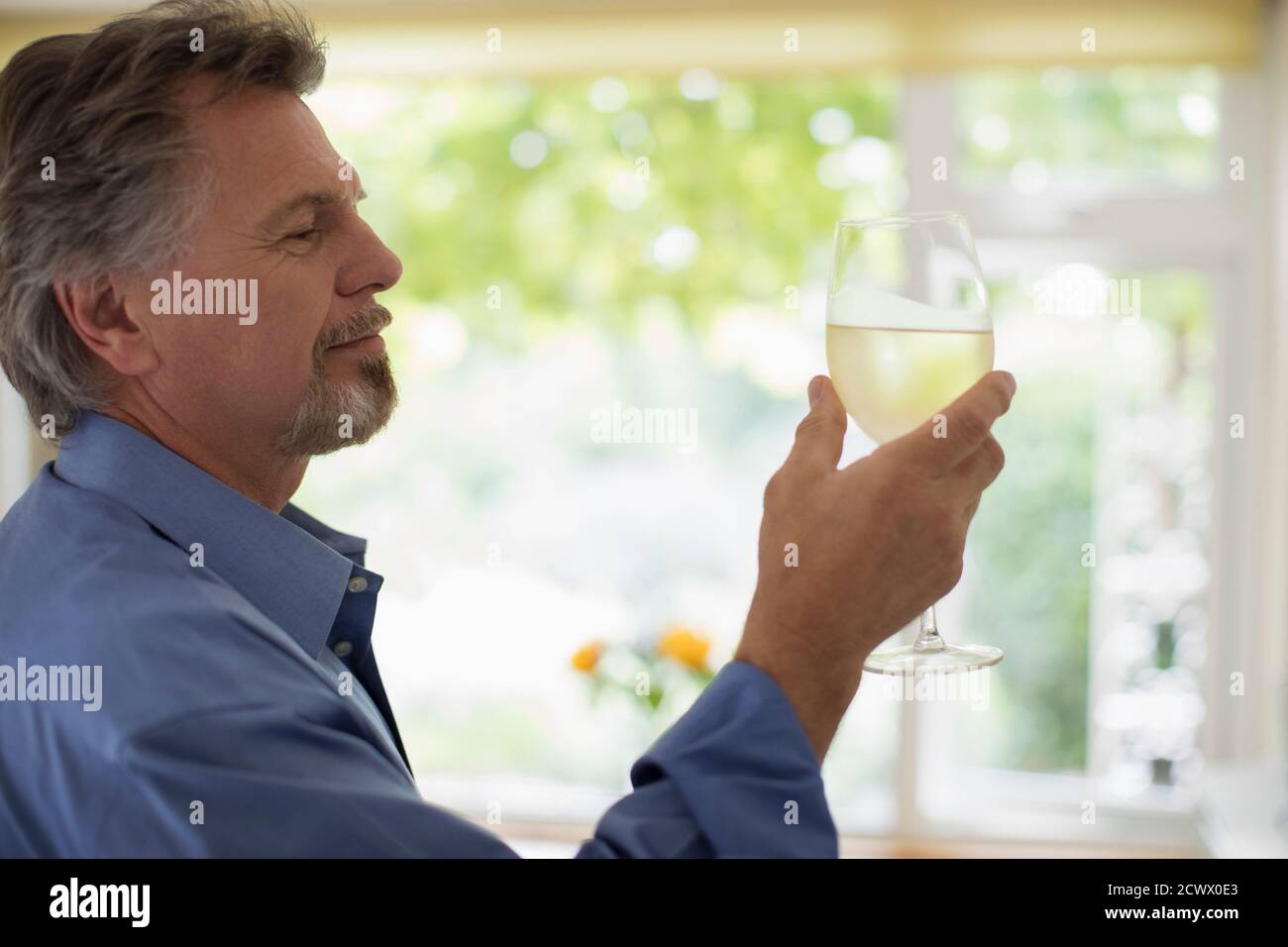 Älterer Mann trinkt Weißwein Stockfoto