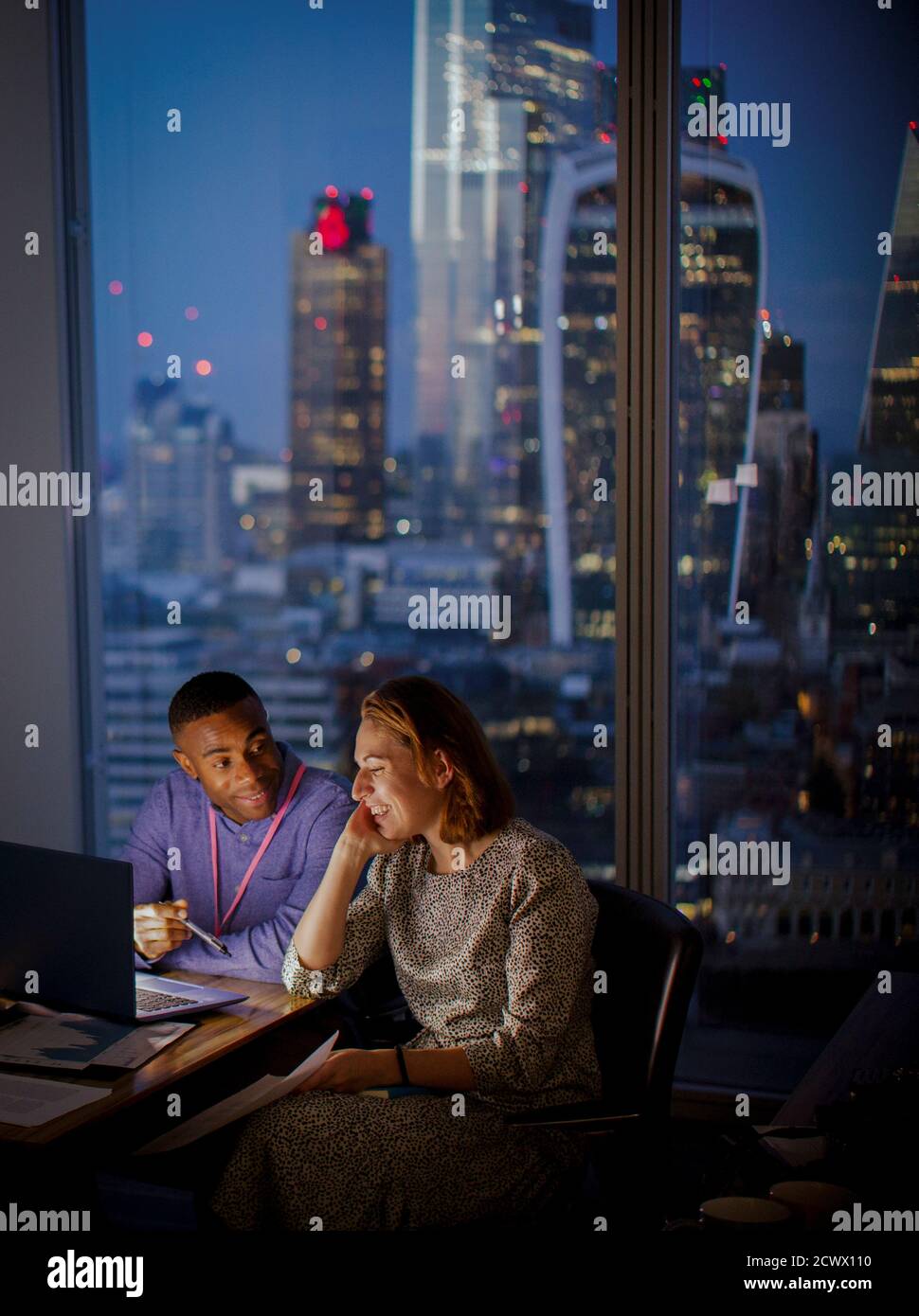 Geschäftsleute, die spät am Laptop im Hochhaus in London arbeiten Stockfoto