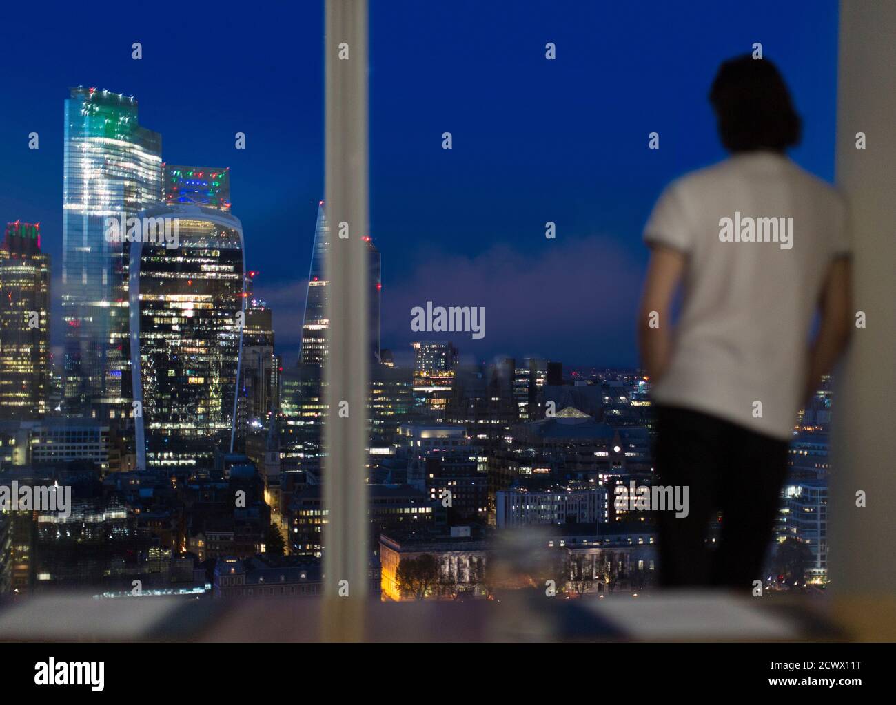 Geschäftsmann, der spät am Bürofenster in einem Hochhaus, London, Großbritannien, arbeitet Stockfoto