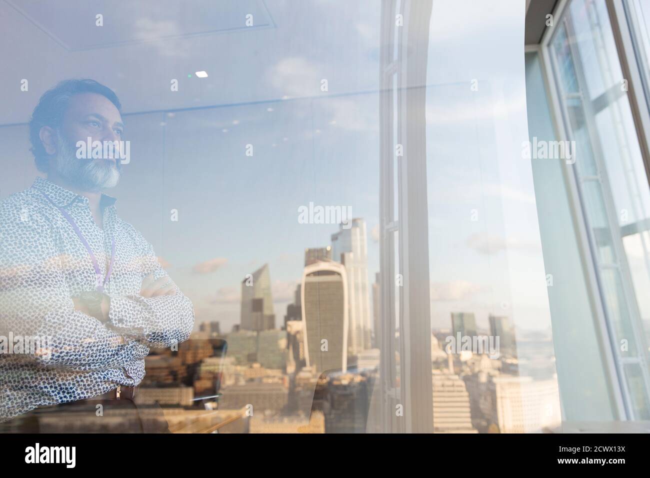 Durchdachter Geschäftsmann mit Blick auf das Bürofenster im Hochhaus, London, Großbritannien Stockfoto