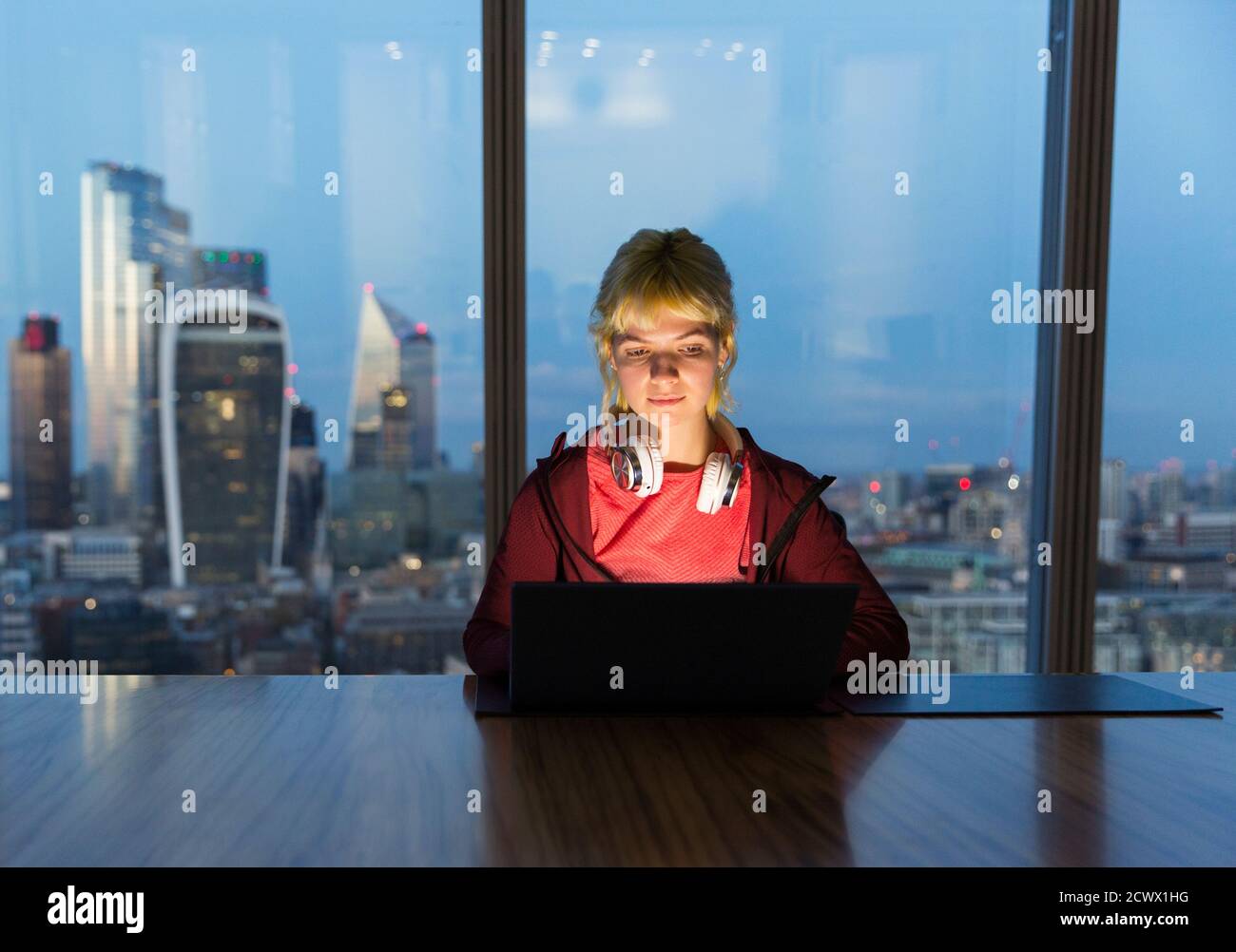 Geschäftsfrau, die spät am Laptop in einem Hochhaus in London, Großbritannien, arbeitet Stockfoto