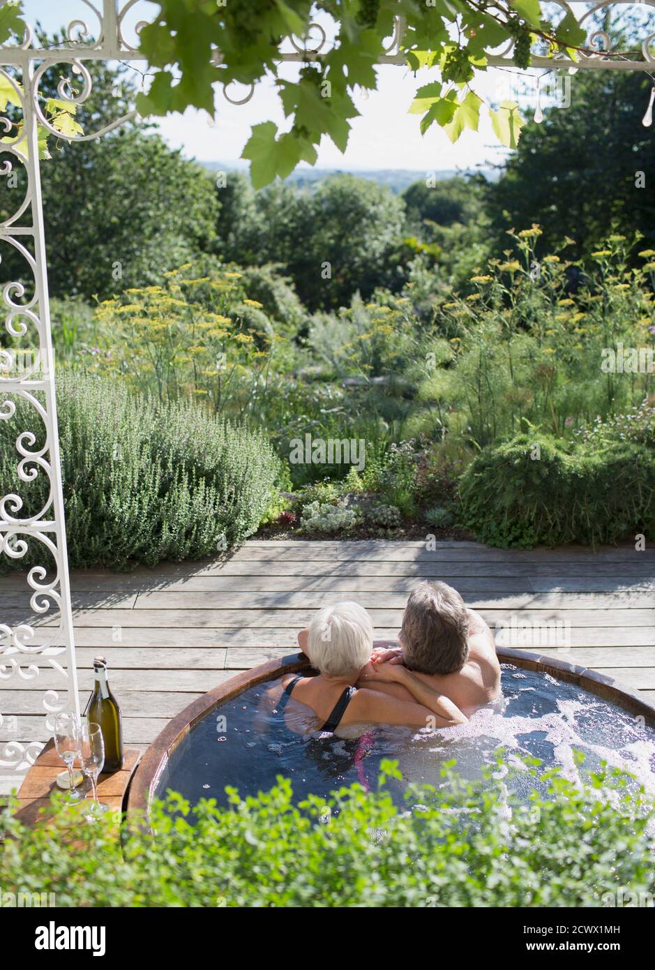 Sorgloses Paar, das sich im Whirlpool auf der sonnigen Sommerterrasse entspannen kann Stockfoto