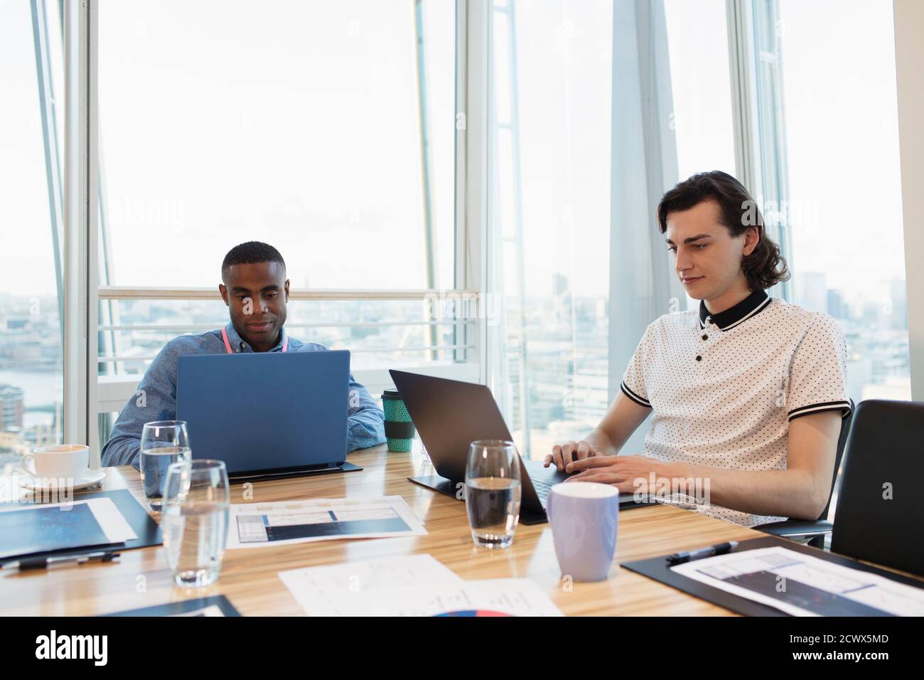 Geschäftsleute, die im Hochhauskonferenzraum an Laptops arbeiten Stockfoto