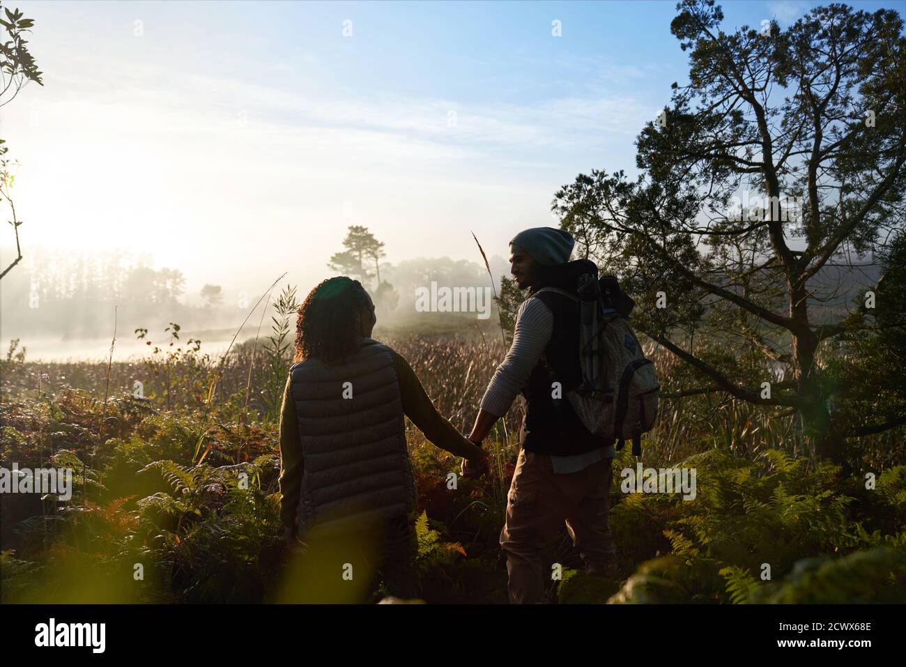 Junges Paar Wandern in ruhiger sonniger nebliger Landschaft Stockfoto