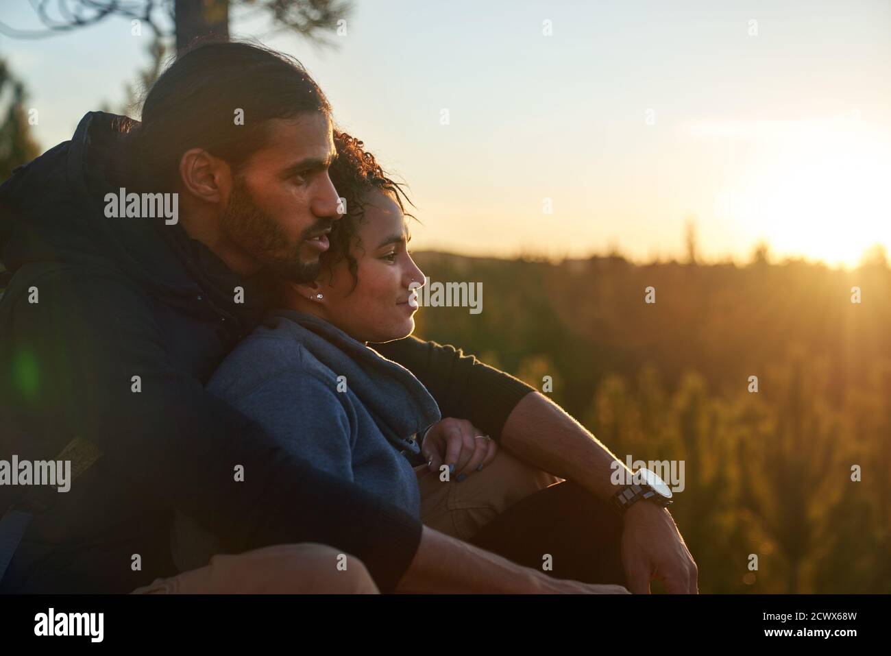 Liebevolles ruhiges junges Paar, das sich bei Sonnenuntergang in der Natur entspannt Stockfoto