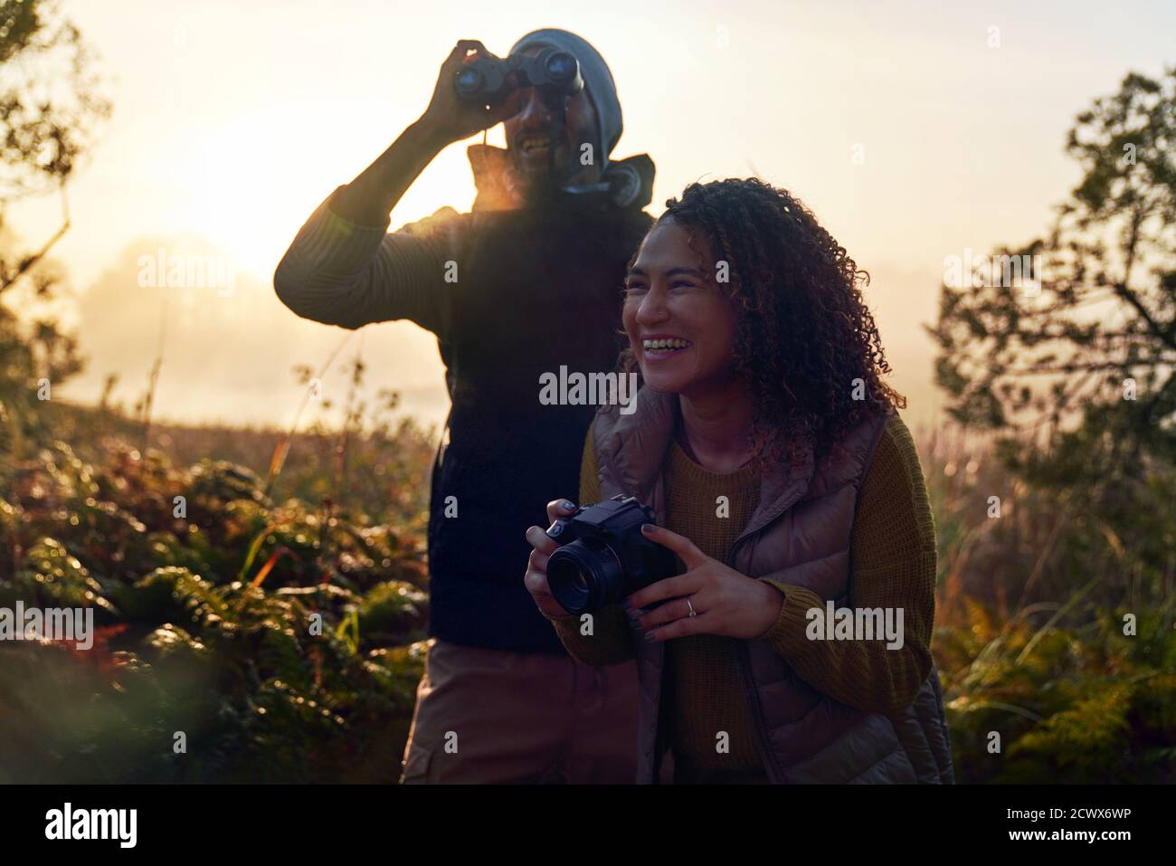 Glückliches junges Wanderpaar mit Kamera und Fernglas in der Natur Stockfoto