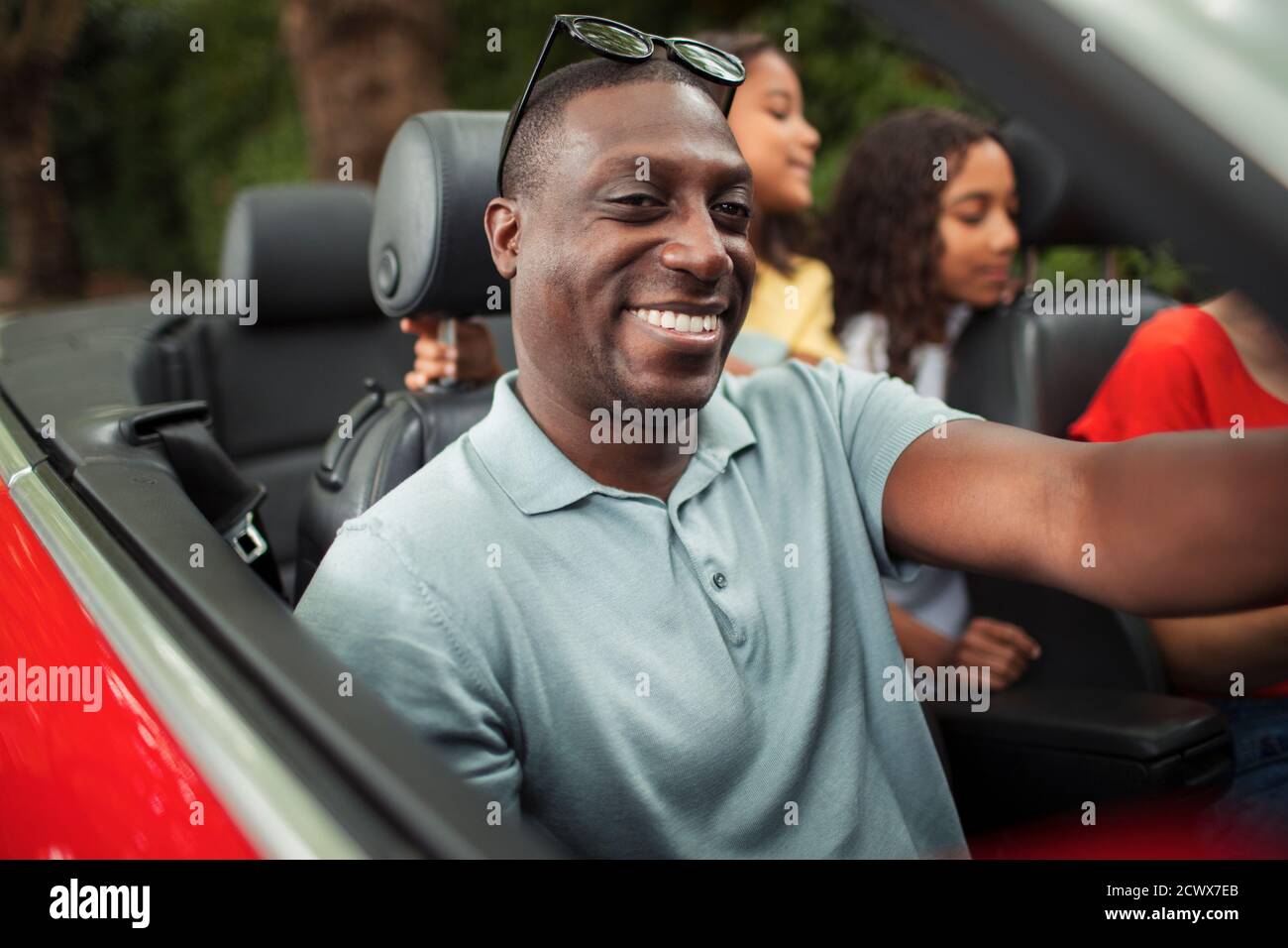 Glücklicher Mann fährt im Cabrio mit Familie Stockfoto