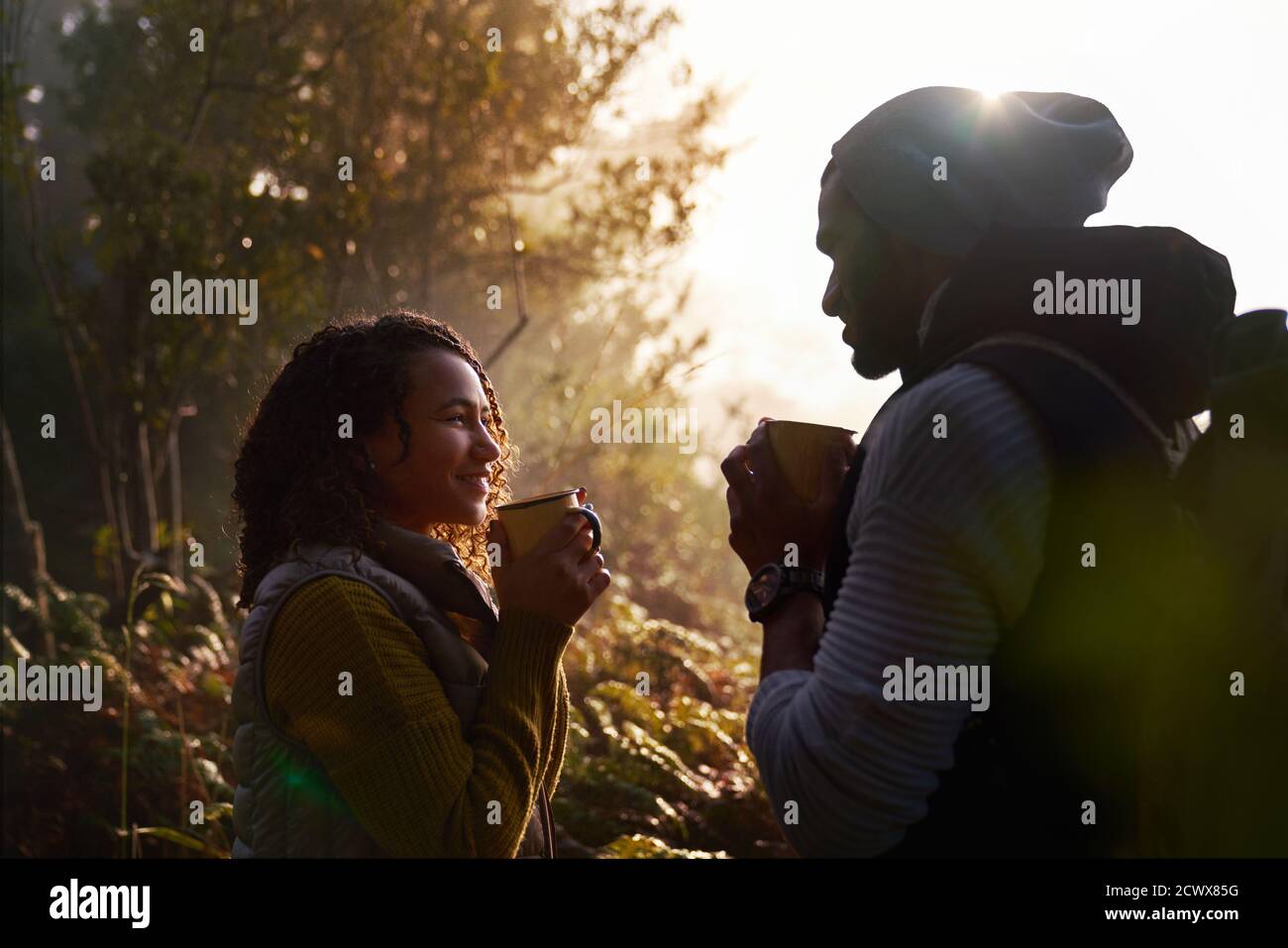 Glückliches junges Wanderpaar trinkt Kaffee in sonnigen Wäldern Stockfoto