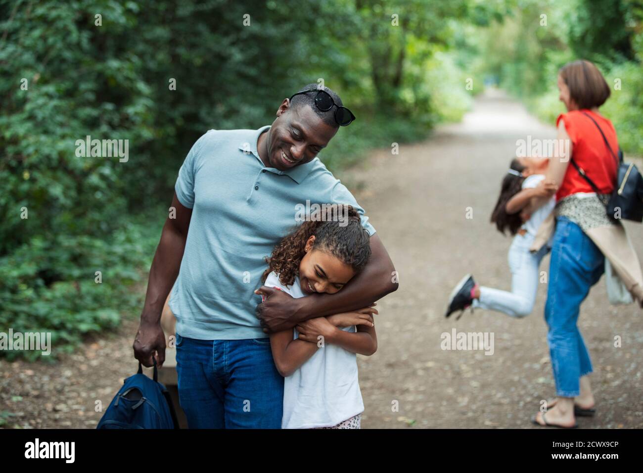 Glücklicher Vater und Tochter umarmen auf Parkweg Stockfoto