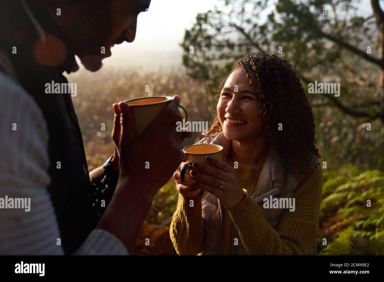 Glückliches junges Paar trinkt Kaffee in sonnigen Wäldern Stockfoto