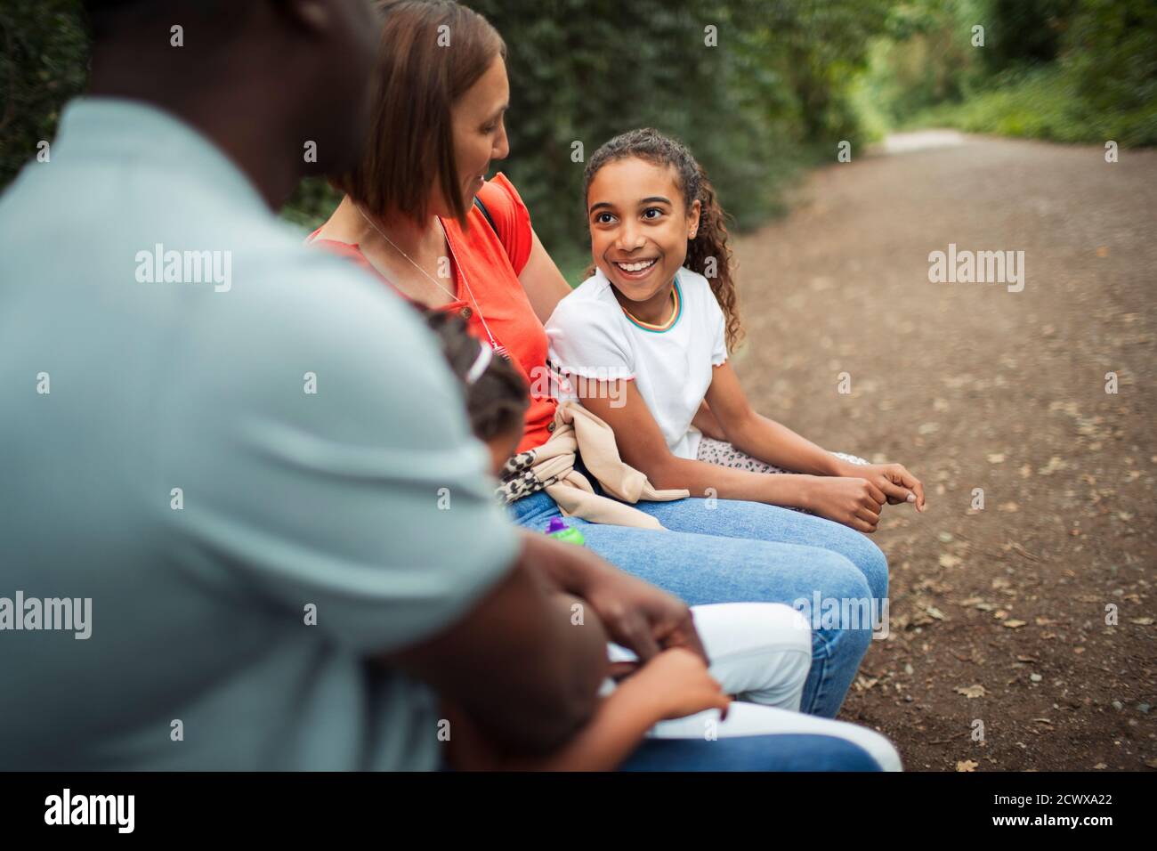 Fröhliche Familie im Gespräch auf Parkbank Stockfoto