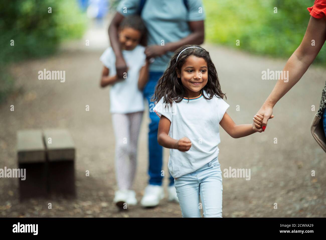 Glückliches Mädchen zu Fuß mit der Familie auf dem Weg im Park Stockfoto