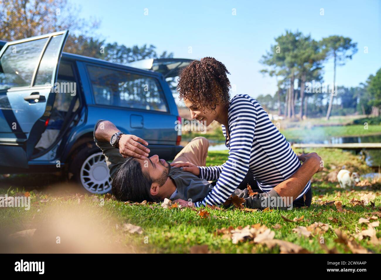 Liebevolles junges Paar, das im sonnigen Herbstgras liegt Stockfoto