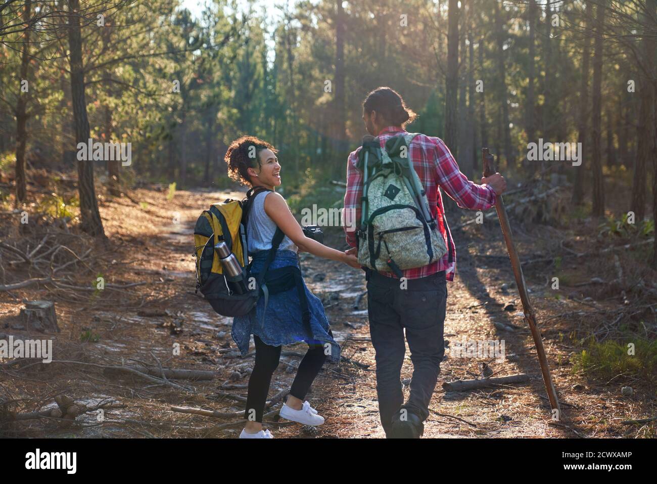 Glückliches junges Paar mit Rucksäcken Wandern in sonnigen Wäldern Stockfoto