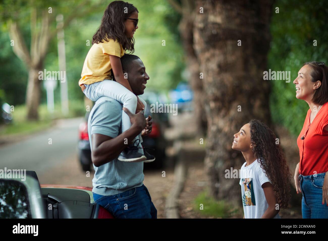 Glückliche Familie, die sich vor dem Cabrio auf der Straße unterhielt Stockfoto