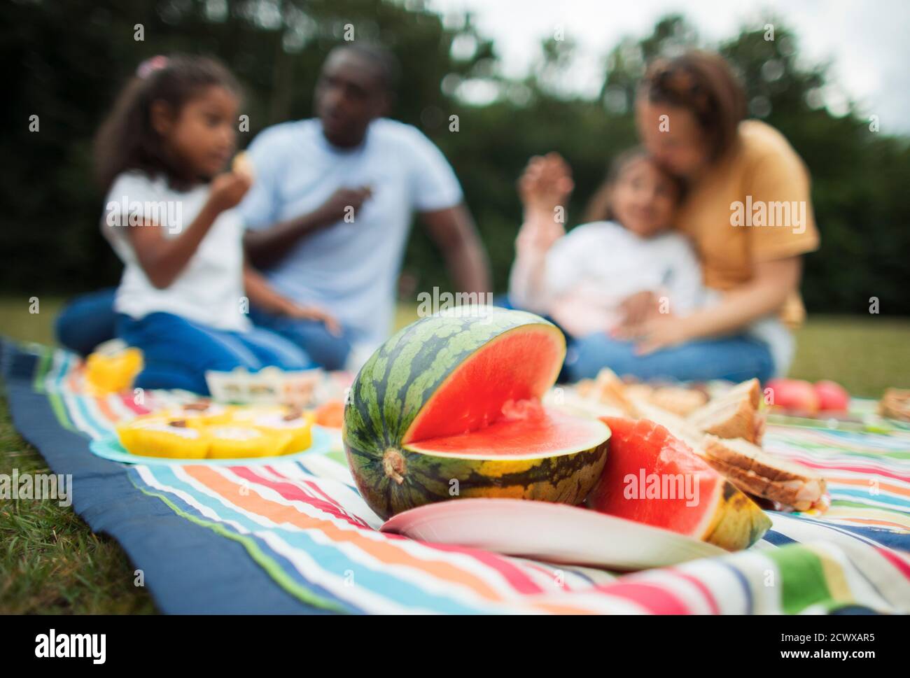 Familie genießt frische Wassermelone auf Picknick-Decke im Park Stockfoto