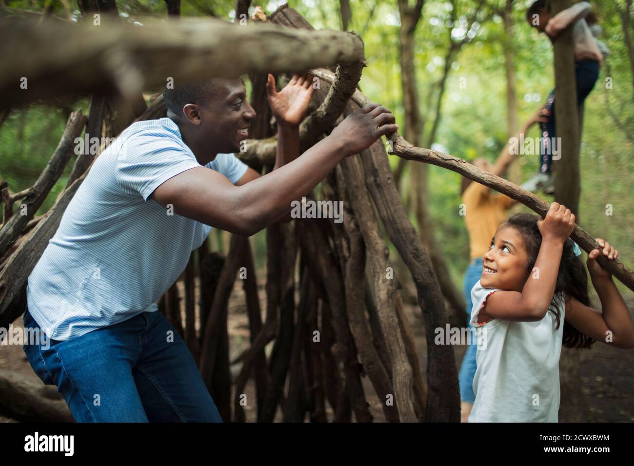Vater und Tochter bauen Tipi mit Ästen in Wäldern Stockfoto