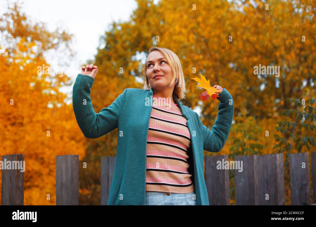 Glückliche blonde Frau in blauem Mantel genießen Spaziergang im Herbst Park. Herbstkonzept. Stockfoto