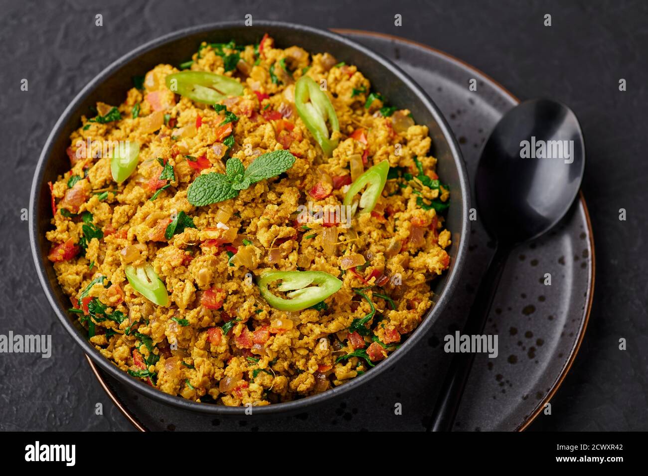 Masala Egg Bhurji oder Muttai Podimas in schwarzer Schale auf dunkler Schieferplatte. Anda Bhurji ist indische Küche Rühreier Gericht mit Gewürzen. Asiatische Küche a Stockfoto