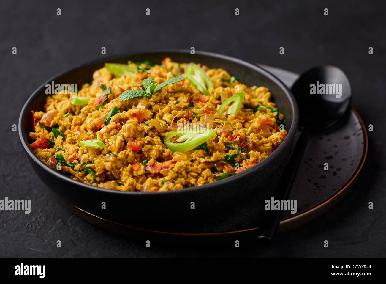 Masala Egg Bhurji oder Muttai Podimas in schwarzer Schale auf dunkler Schieferplatte. Anda Bhurji ist indische Küche Rühreier Gericht mit Gewürzen. Asiatische Küche a Stockfoto