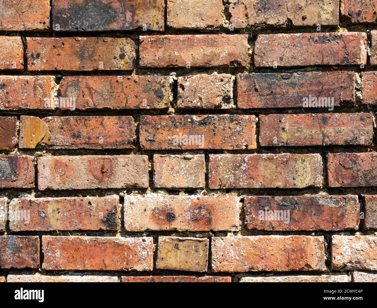 Eine rustikale, gealterte, wettergetragene rote Ziegelwand für einen strukturierten grafischen Designhintergrund Stockfoto