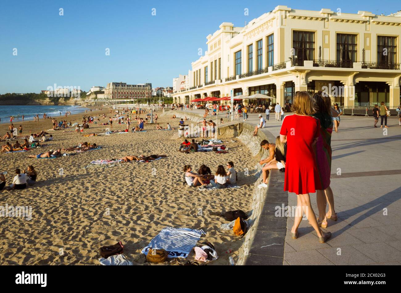 Biarritz, französisches Baskenland, Frankreich - 19. Juli 2019: Zwei Frauen sehen sich La Grande Plage an, den größten Strand der Stadt mit dem Art Deco Casino von Bi Stockfoto