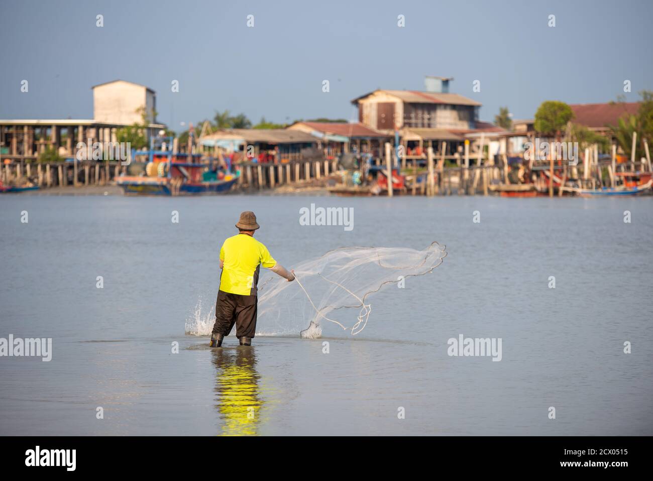 Sekinchan, Selangor/Malaysia - 06 2019. Oktober: Ein Fischer wirft das Netz. Hintergrund ist Fischerdorf. Stockfoto