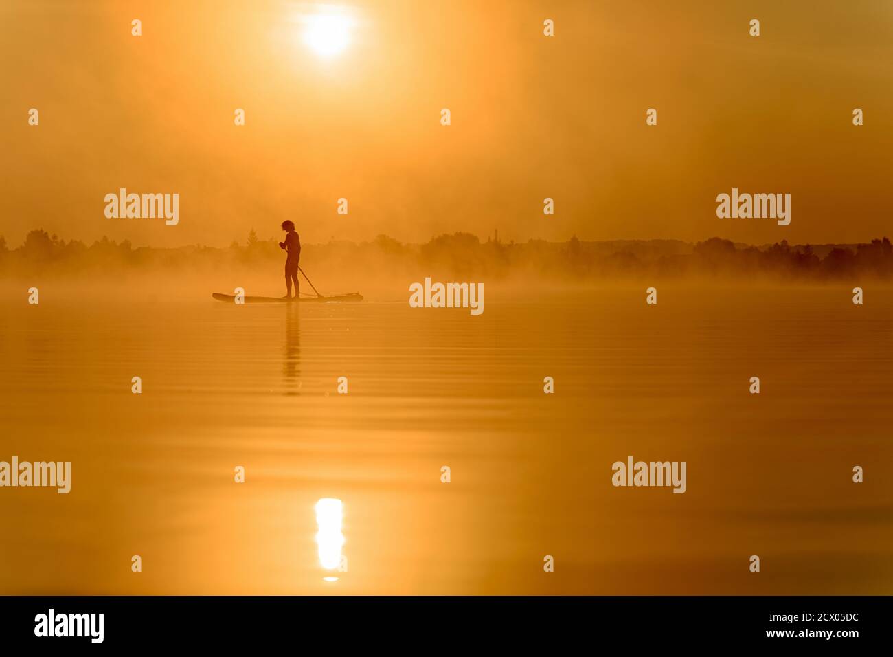 Junger Mann mit Paddle Board zum Schwimmen am See Stockfoto