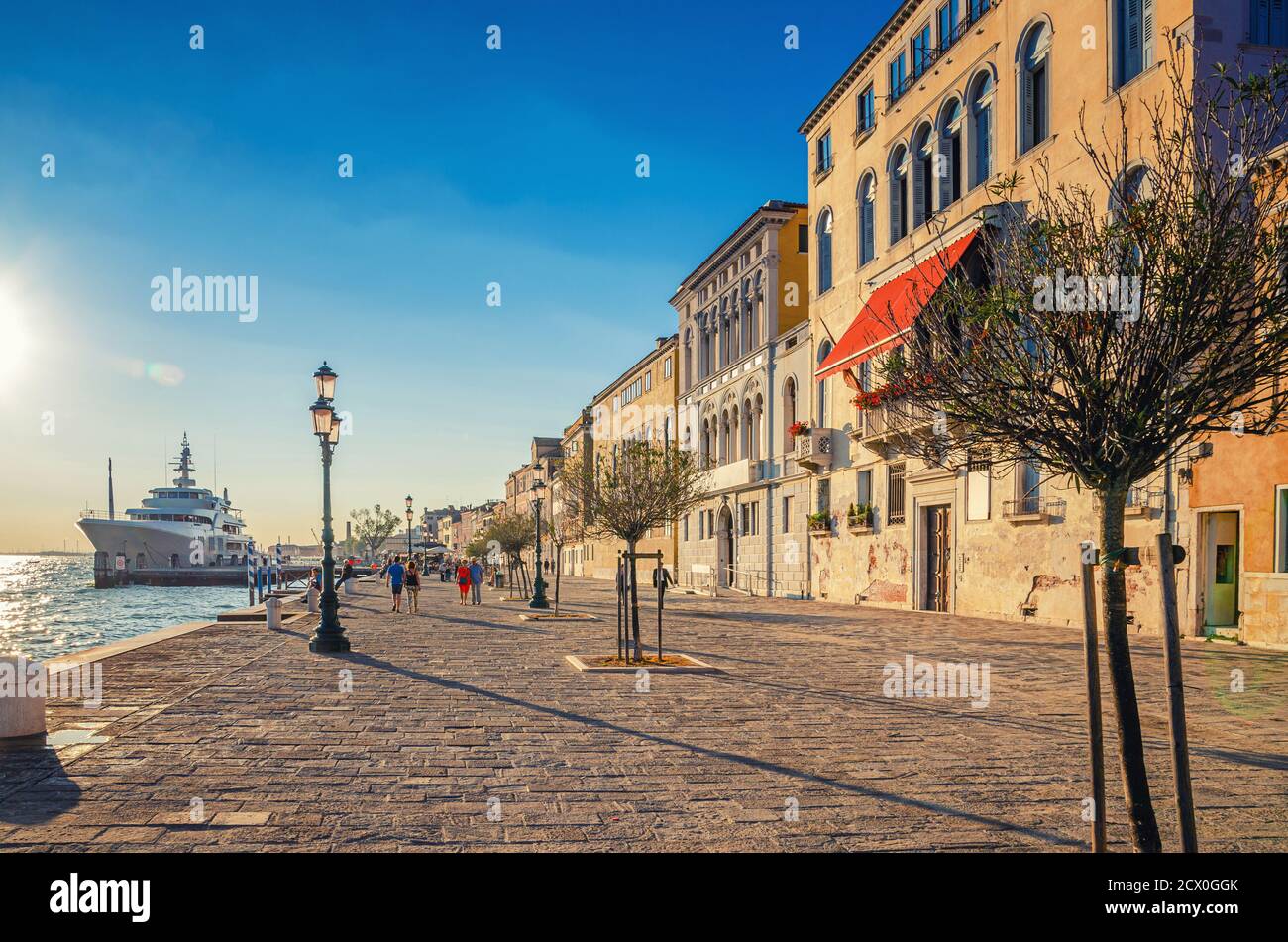 Menschen Touristen sind zu Fuß entlang Uferpromenade Fondamenta Zattere Al Ponte Lungo mit Bäumen und Yacht im Wasser des Giudecca Kanal am Wasser in Venedig historischen Zentrum, Italien Stockfoto