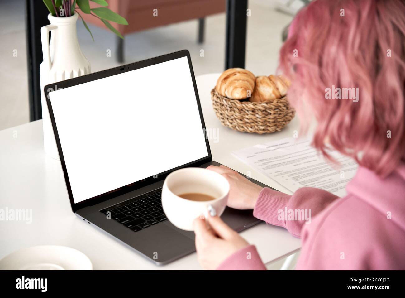 Junge Frau sitzen am Küchentisch trinken Kaffee verwenden Laptop-Modell weißen Bildschirm. Stockfoto