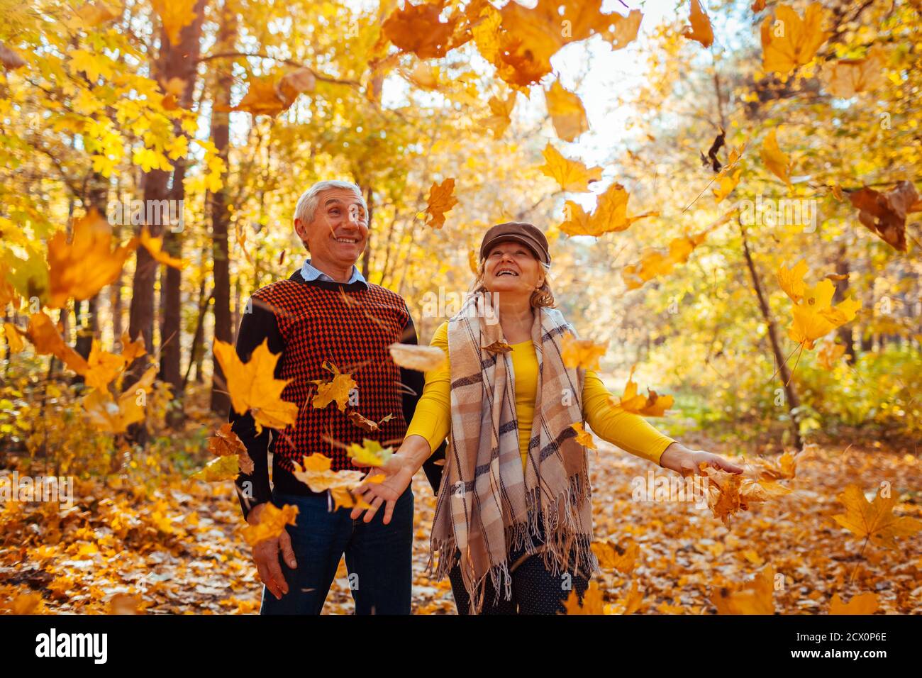Herbstsaison. Familienpaar wirft Blätter im Herbstwald. Ältere Menschen haben Spaß im Freien genießen Natur spielen Stockfoto