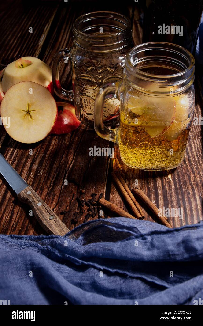 Ein Holztisch mit Äpfeln und einem leckeren Apfelwein. Typisches Herbstgetränk Stockfoto