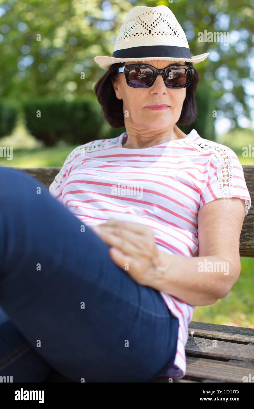 Ältere Frau, die sich auf der Parkbank entspannt Stockfoto