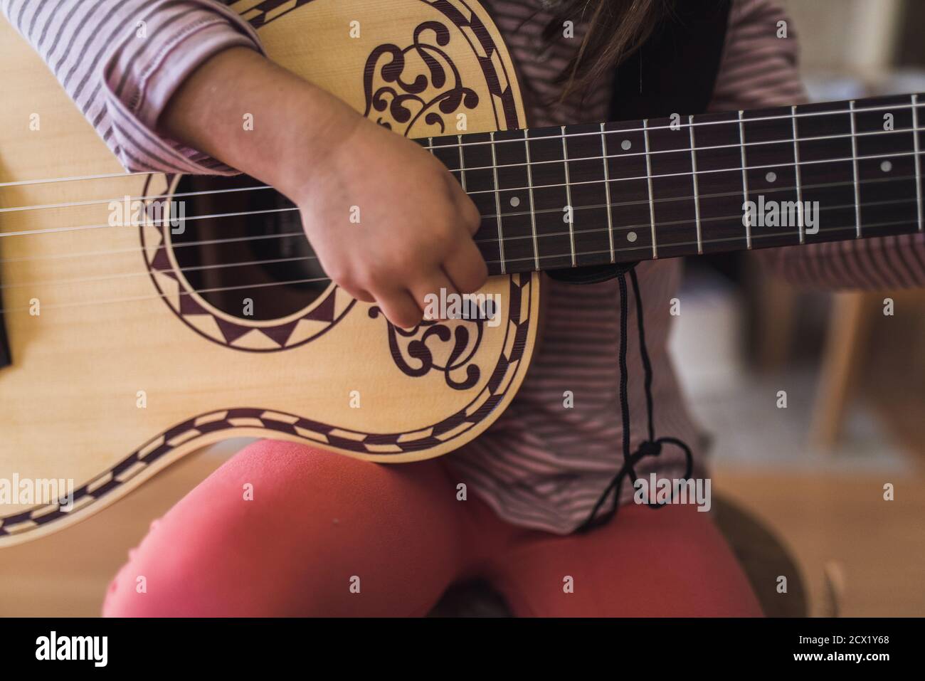 Kunstvolle 6-saitige Akustikgitarre, die von einem 6-jährigen Kind gehalten wird Stockfoto