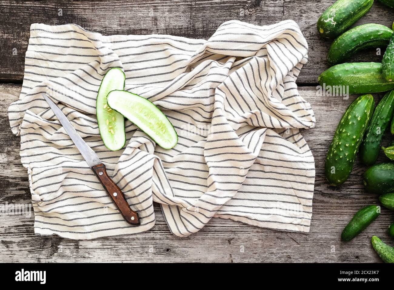 Draufsicht frische Bauerngurken, Messer, Handtuch, Gurke auf Holzhintergrund, Mockup, Kopierraum. Stockfoto