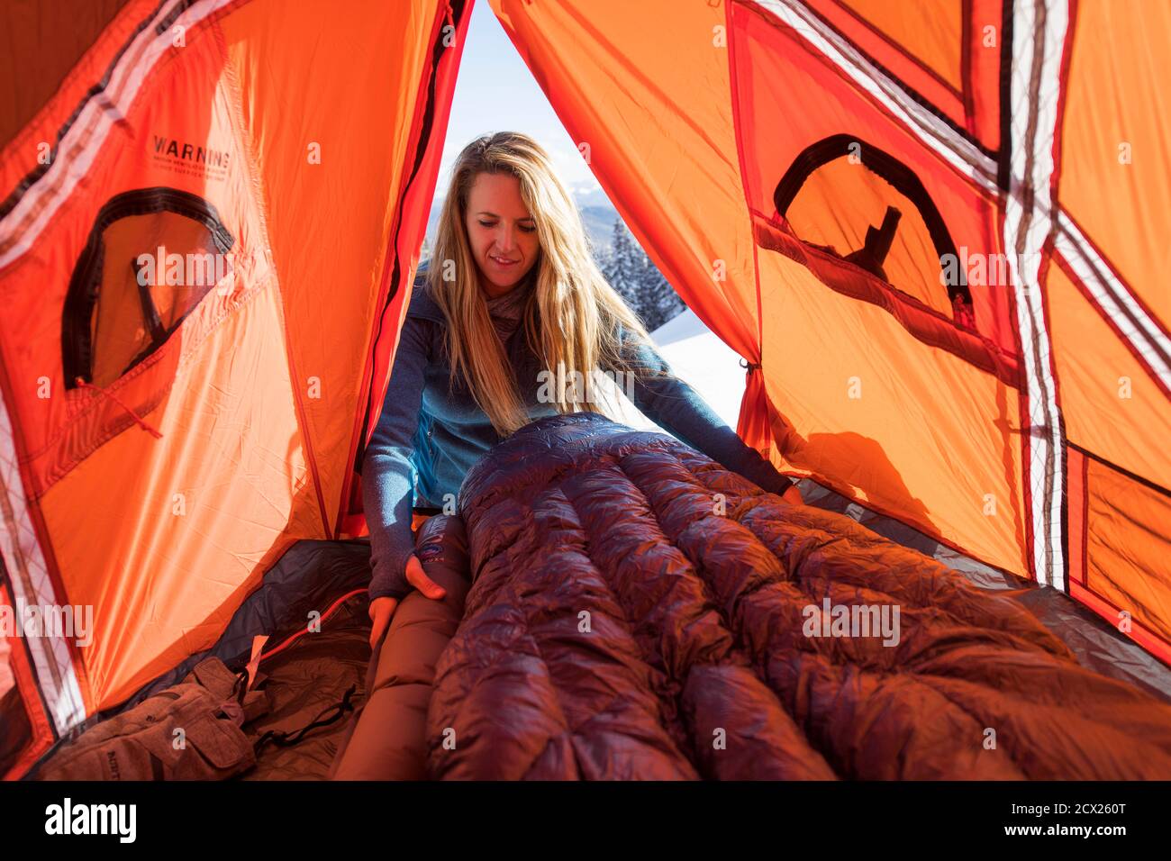 Junge Wanderin arrangiert aufblasbare Matratze im Zelt Stockfoto