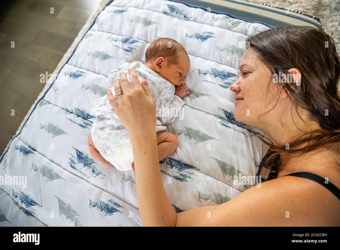 Liebevolle Mutter berührt sanft neugeborenes Baby auf dem Bauch liegend. Stockfoto